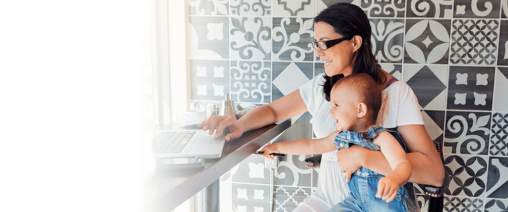 Mujer con bebé sentada frente a computadora