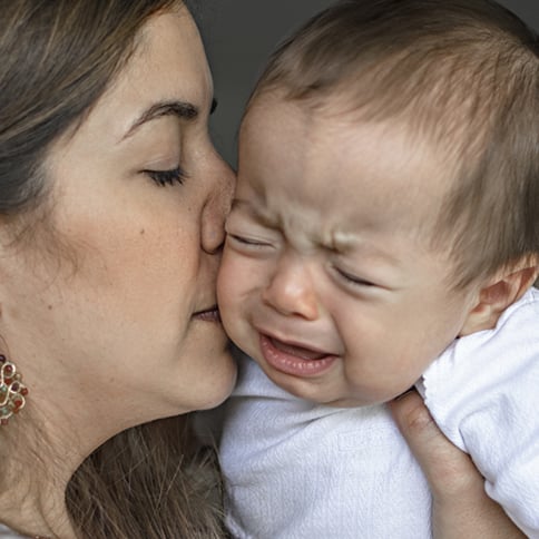 Mamá besando a bebé llorando