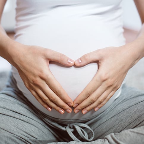 Mujer embarazada con manos en su abdomen